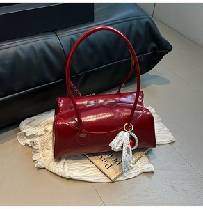Détail du sac Boston rouge brillant avec breloque cerise sur fond intérieur élégant