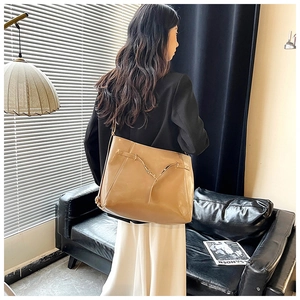 Detail of khaki patent leather tote bag with elegant golden V-shaped metal buckle