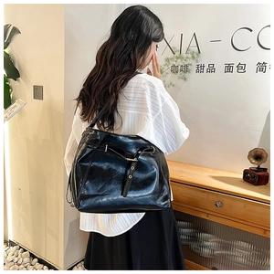 Detail of a large capacity black glossy leather tote bag with stylish metal buckle straps