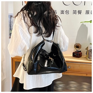 Close-up of a glossy black leather hobo bag worn as a backpack in a cozy indoor setting