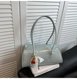 Détail du sac à main bleu clair en cuir verni avec charms cerise et dentelle