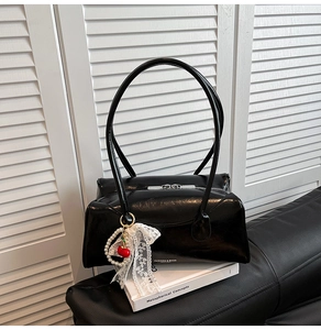 Détail d'un cabas noir verni avec breloque cerise en perles et nœud décoratif en dentelle