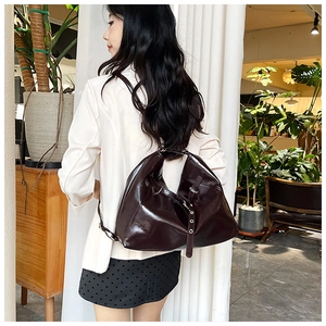 Model wearing dark coffee shiny leather backpack with adjustable metal buckles and straps