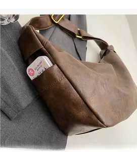 Detailed view of brown PU leather bag with side pocket and golden metal hardware adjustment