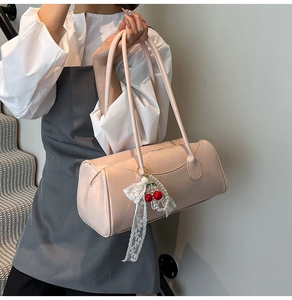 Détail du sac cylindre rose avec pendentif cerise en perles et nœud en dentelle