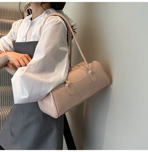 Détail d'un sac à bandoulière rectangulaire rose pâle avec texture en cuir lisse sur un modèle