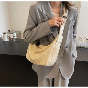 Detailed view of beige crescent bag featuring cracked texture and adjustable gold buckle