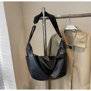 Detail view of large black soft leather hobo bag with gold hardware and wide shoulder strap