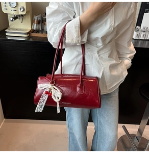 Détail du sac Boston rouge avec charm en dentelle blanche et pendentif cerise