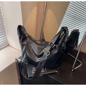 Detail of soft black PU leather texture and gold buckle on a large hobo bag