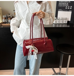 Détail du sac à main rouge brillant avec nœud en dentelle blanche et cerises