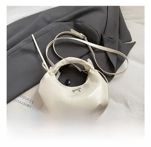 Détail du sac en similicuir crème avec nœud argenté sur un blazer gris élégant