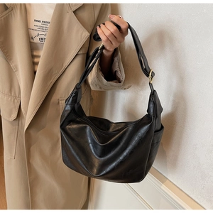 Detail of adjustable strap with gold buckle on a black textured leather hobo bag