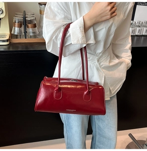 Détail du sac Boston bordeaux en cuir brillant avec logo argenté et texture fine