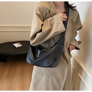Detail view of large black slouchy faux leather shoulder bag with vintage pleated texture