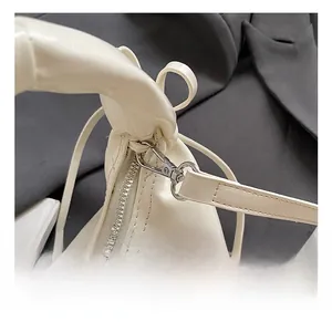 Gros plan sur le fermoir argenté et les coutures précises du sac à main en cuir beige