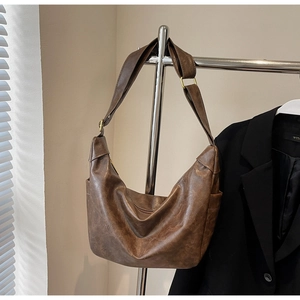 Detail of vintage brown textured leather hobo bag with gold buckle on a wide shoulder strap