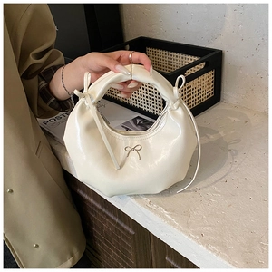 Détail d'un sac demi-lune beige avec nœud doré et texture plissée élégante