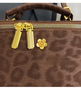 Detail of leopard print suede mini box bag with golden floral charm and dual zippers