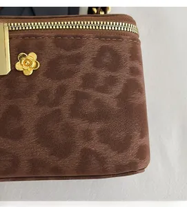 Close-up of leopard print bag texture with golden camellia charm and zipper detail