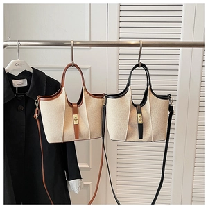 Close-up of beige canvas bucket bag featuring metal twist lock and leather trim details