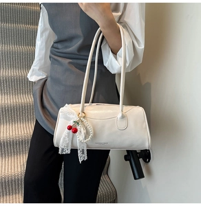 Détail d'un sac à main blanc en cuir avec breloque cerise et nœud en dentelle chic
