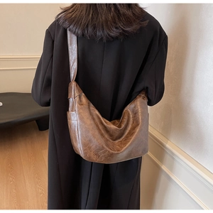 Brown leather hobo bag worn over the shoulder showing its large capacity and soft texture