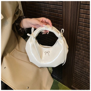 Détail du sac demi-lune blanc perle avec nœud métallique et rubans en cuir