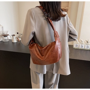 Brown large capacity soft leather shoulder bag worn by model in a cafe setting