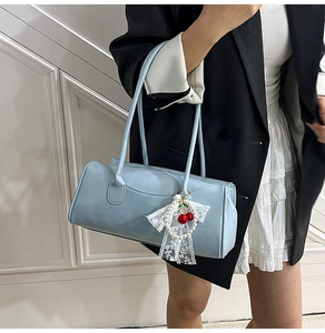 Détail du sac Boston bleu clair avec breloque cerise et perle sur cuir synthétique grainé