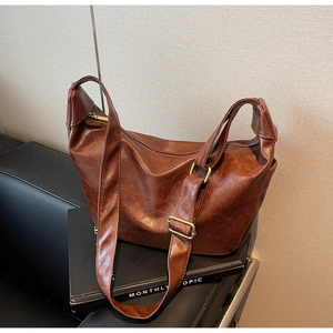 Detail of caramel brown faux leather shoulder bag with lychee texture and gold hardware