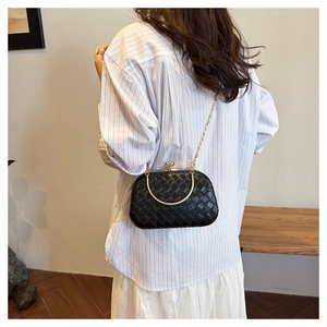 Detail of black woven crossbody bag featuring a vintage metal clasp and chain strap