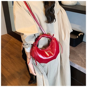 Détail du sac croissant rouge avec boucle nœud argenté sur robe beige