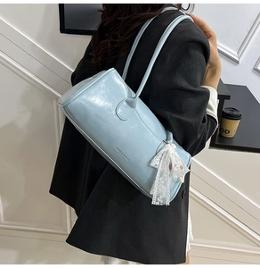 Détail d'un sac à main bleu clair en cuir brillant avec nœud en dentelle et perles