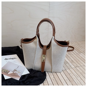 Detail of canvas and brown leather tote bag with gold buckle and adjustable strap