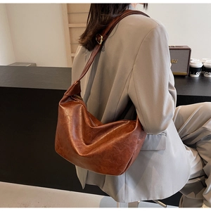 Detail of vintage brown oil wax leather hobo bucket bag with adjustable gold buckle finish