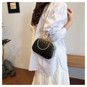 Detail of woven black PU leather clutch with golden metal handle and chain strap
