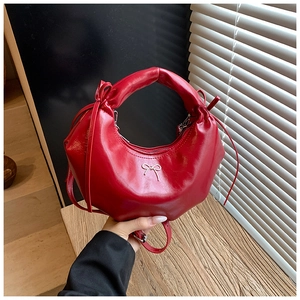 Détail du sac demi-lune rouge avec nœud métallique argenté et lanières à glands