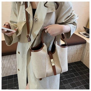 Detail of canvas and leather bucket bag featuring a golden twist-lock and brown trim