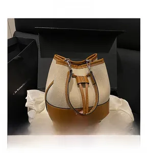 Close-up of canvas bucket bag with brown leather drawstring and silver metal hardware