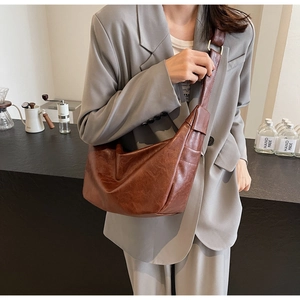 Detailed side view of large brown faux leather dumpling bag with metal adjustment buckle