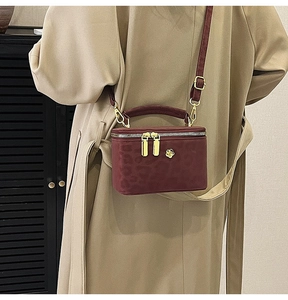 Detail of burgundy leopard embossed mini box bag with golden floral metal hardware