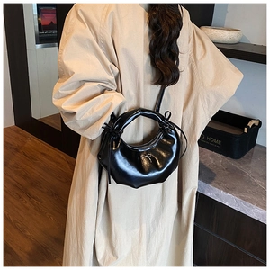 Sac sous le bras noir brillant avec nœud doré et finition élégante en cuir verni