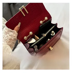 Detail view of red crocodile-pattern crossbody bag interior with multiple compartments