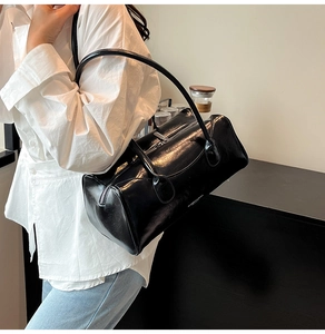 Vue latérale d'un sac Boston noir brillant avec fines anses et lettrage minimaliste