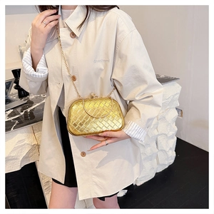 Close-up of golden woven texture evening clutch with diamond-studded metal lock and chain