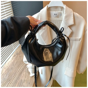 Vue détaillée du sac demi-lune en cuir noir avec nœud doré et bandoulière réglable