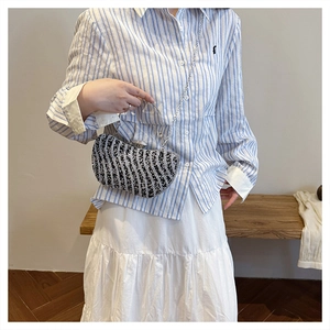 Dettaglio pochette da sera a mezzaluna con strass bianchi e neri e manico in metallo