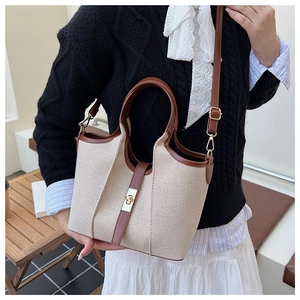 Detail of canvas and brown leather tote with golden twist lock and adjustable strap