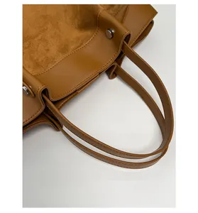 Close-up of the brown tote bag featuring mixed leather textures and silver metal buckle